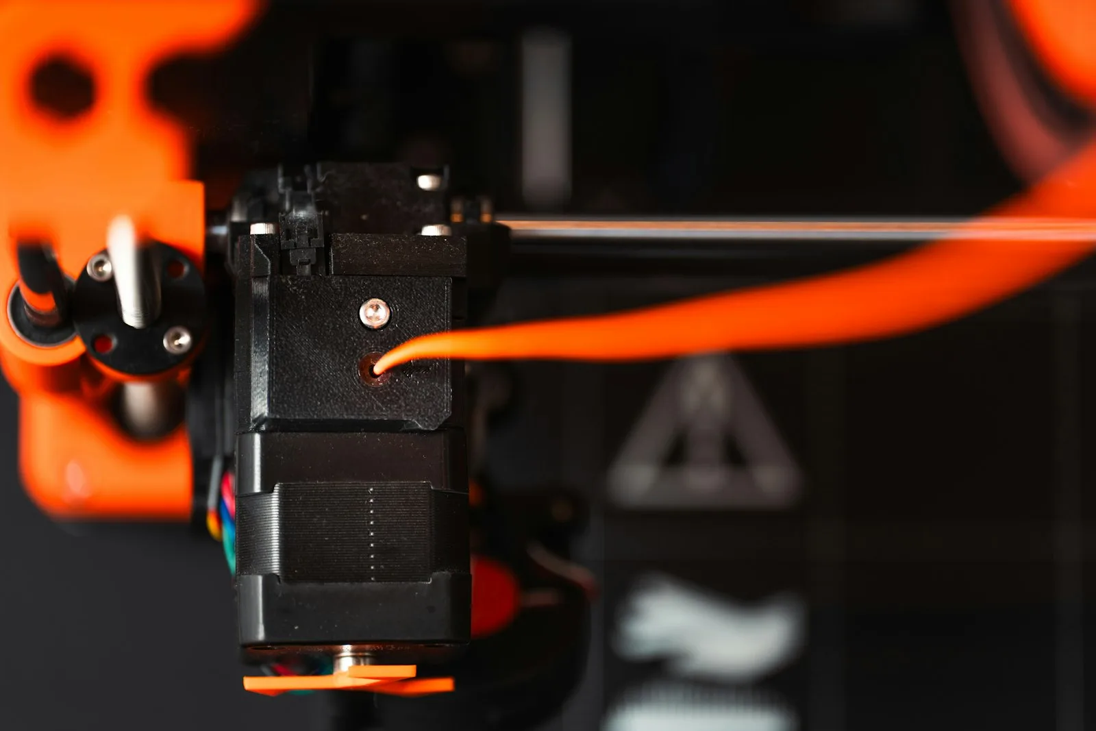 Сопло 3D-принтера печатает оранжевую деталь